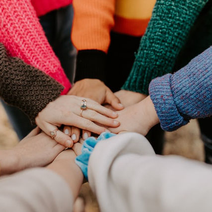 different hands wearing knitted sweaters